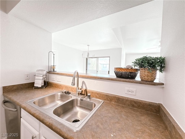 kitchen featuring a textured ceiling, a ceiling fan, white cabinets, and a sink