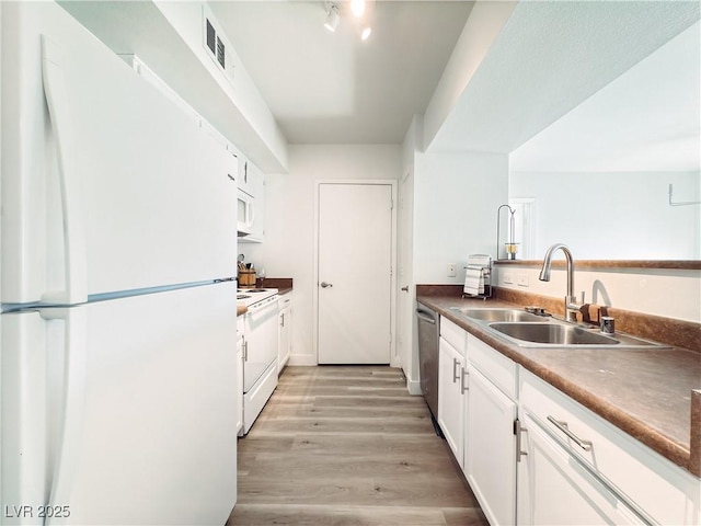 kitchen featuring white appliances, a sink, visible vents, white cabinets, and light wood-type flooring