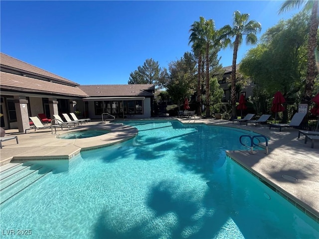 community pool with a patio area and a hot tub