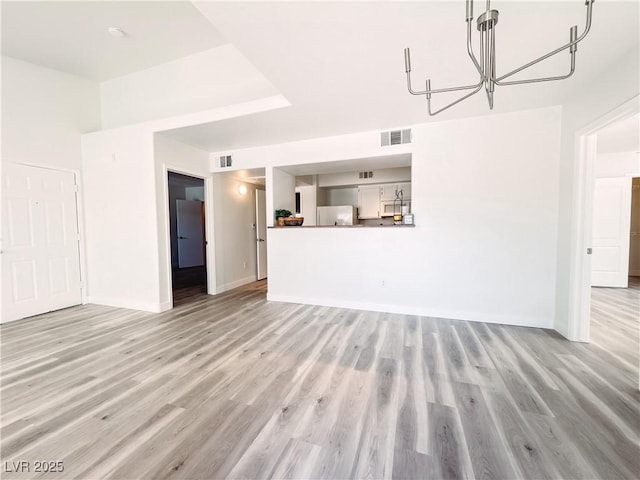 unfurnished living room featuring light wood-style flooring, visible vents, and baseboards