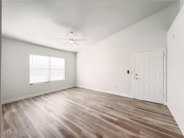 spare room with ceiling fan, vaulted ceiling, wood finished floors, and baseboards