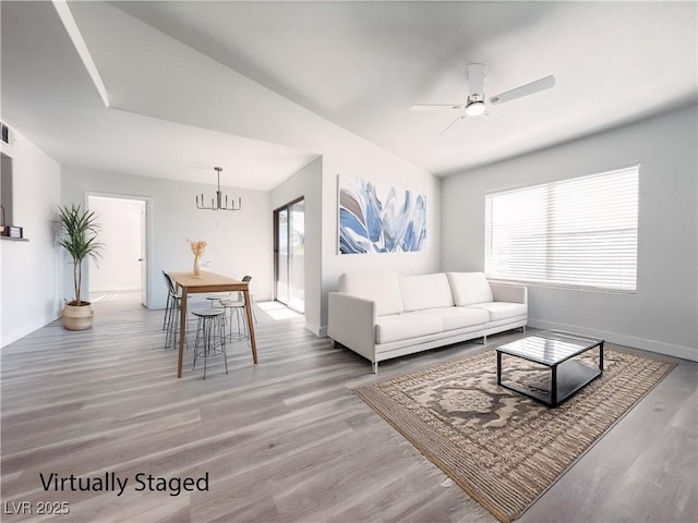 living room with ceiling fan with notable chandelier, a wealth of natural light, visible vents, and wood finished floors