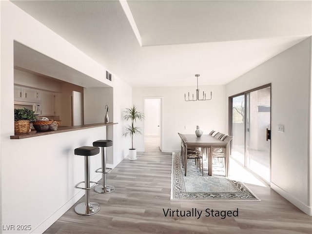 dining area featuring a chandelier, baseboards, visible vents, and light wood-style floors