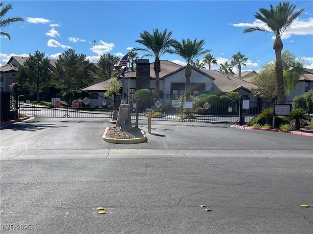 view of street with a gate, a residential view, a gated entry, and curbs