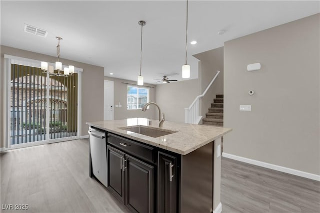 kitchen featuring visible vents, an island with sink, a sink, light wood-style floors, and stainless steel dishwasher