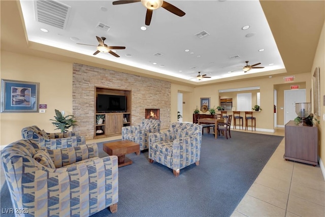 living room with a tray ceiling, light tile patterned flooring, visible vents, and recessed lighting