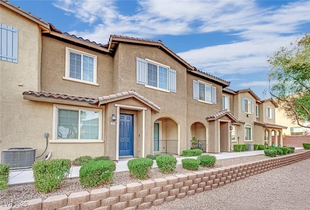 view of property with cooling unit, a tile roof, and stucco siding