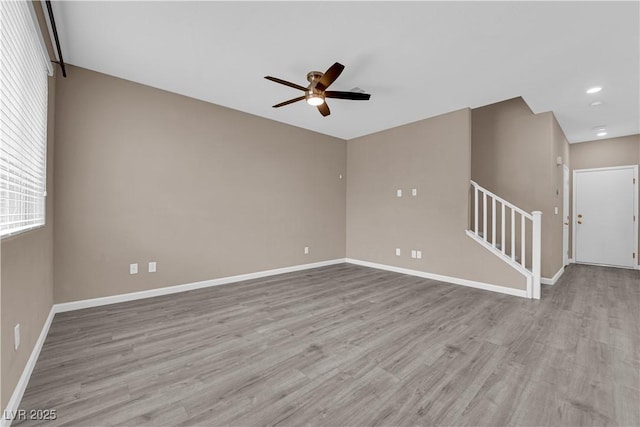 empty room featuring stairs, wood finished floors, and baseboards