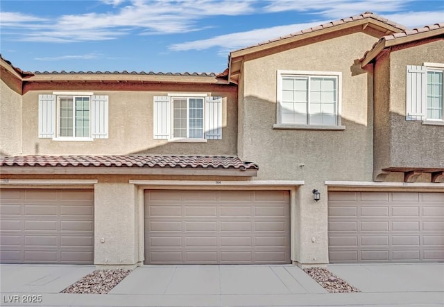 view of property featuring driveway, a garage, and stucco siding