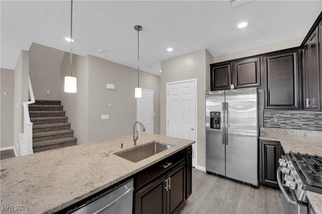 kitchen with stainless steel appliances, decorative backsplash, a sink, and light stone countertops