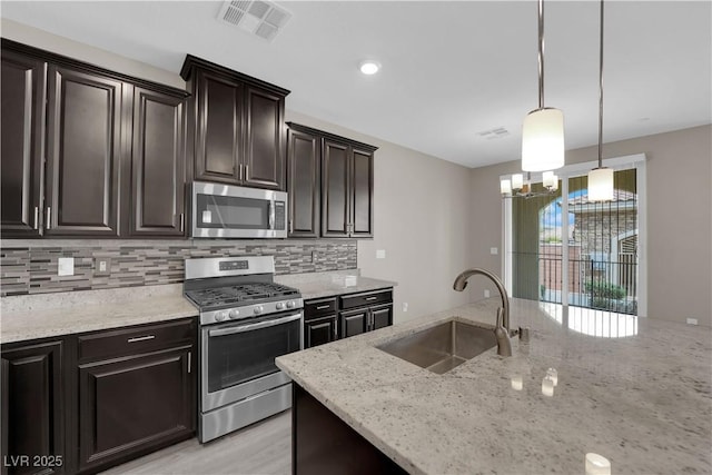 kitchen with stainless steel appliances, a sink, visible vents, and light stone countertops