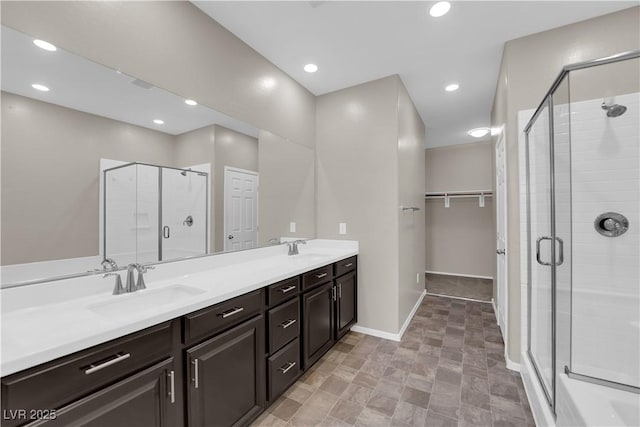 bathroom with double vanity, a stall shower, a sink, and recessed lighting