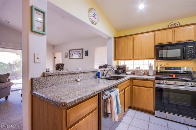 kitchen featuring light stone counters, a peninsula, vaulted ceiling, stainless steel appliances, and a sink