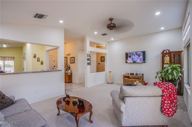 living area with a ceiling fan, light colored carpet, and visible vents