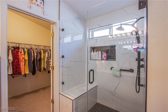 bathroom with a spacious closet and a marble finish shower