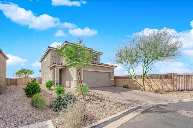 view of front of home featuring decorative driveway, stucco siding, a gate, fence, and a tiled roof