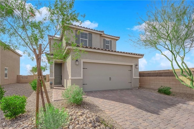 mediterranean / spanish-style house featuring decorative driveway, stucco siding, an attached garage, fence, and a tiled roof