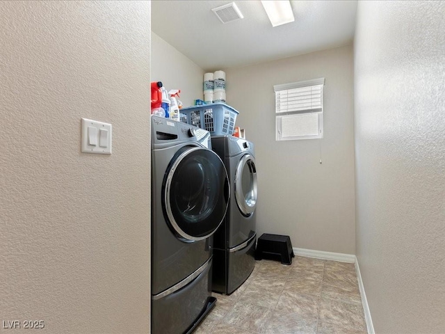 washroom featuring washing machine and clothes dryer, visible vents, a textured wall, laundry area, and baseboards