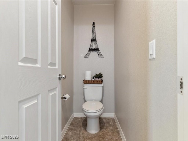 bathroom with baseboards, toilet, and tile patterned floors