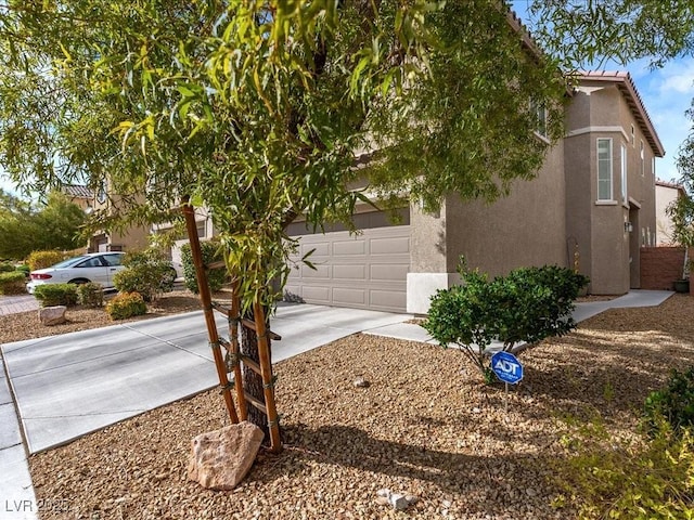 view of property exterior featuring a garage, a tile roof, concrete driveway, and stucco siding