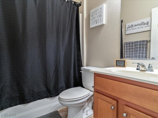 bathroom with shower / bathtub combination with curtain, a textured wall, vanity, and toilet