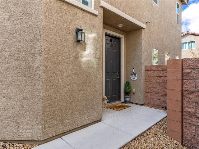 doorway to property with fence and stucco siding