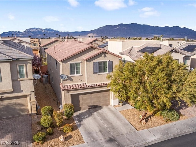 view of front of house with a mountain view, a tiled roof, driveway, a residential view, and stucco siding