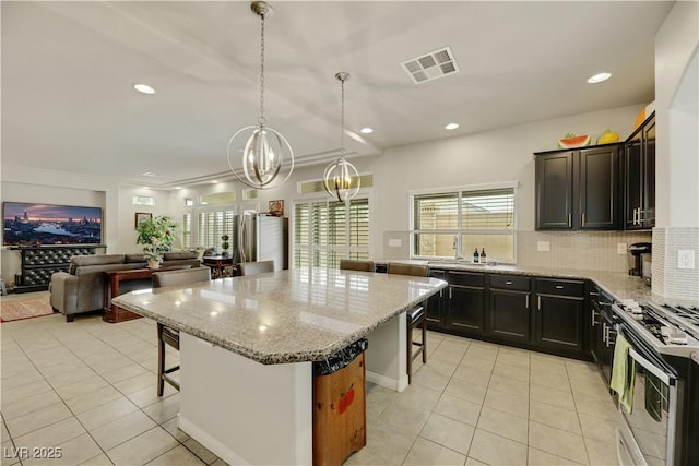 kitchen with stainless steel appliances, visible vents, a kitchen island, and a kitchen breakfast bar