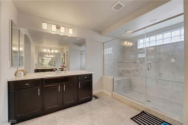 full bathroom with a stall shower, vanity, visible vents, and baseboards