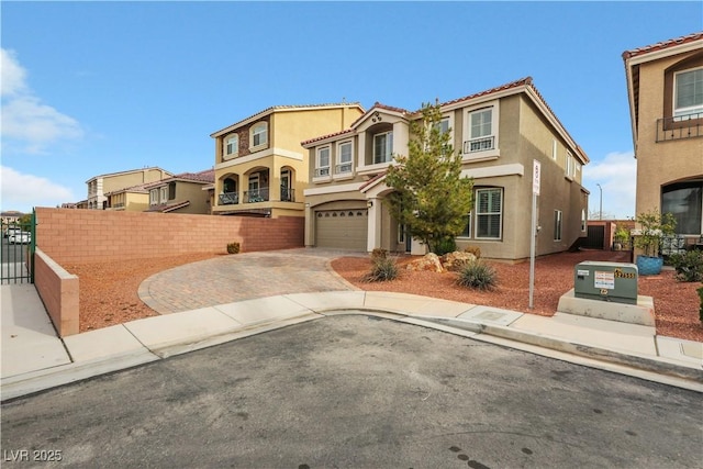 mediterranean / spanish home with decorative driveway, an attached garage, fence, and stucco siding