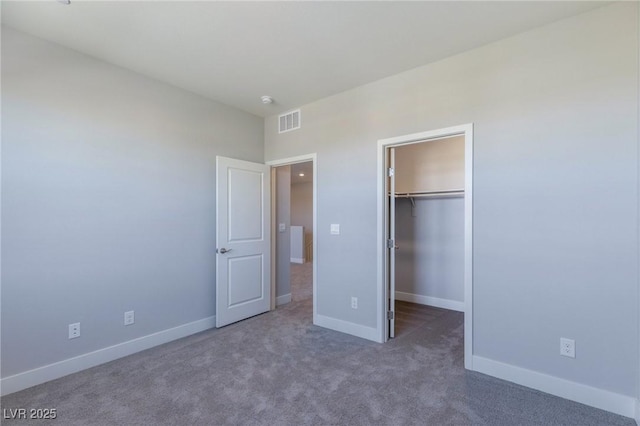 unfurnished bedroom featuring baseboards, visible vents, a walk in closet, carpet floors, and a closet