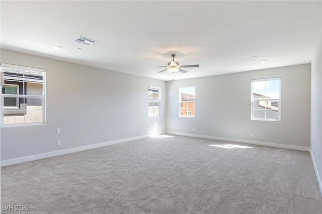 spare room with carpet floors, a ceiling fan, visible vents, and baseboards