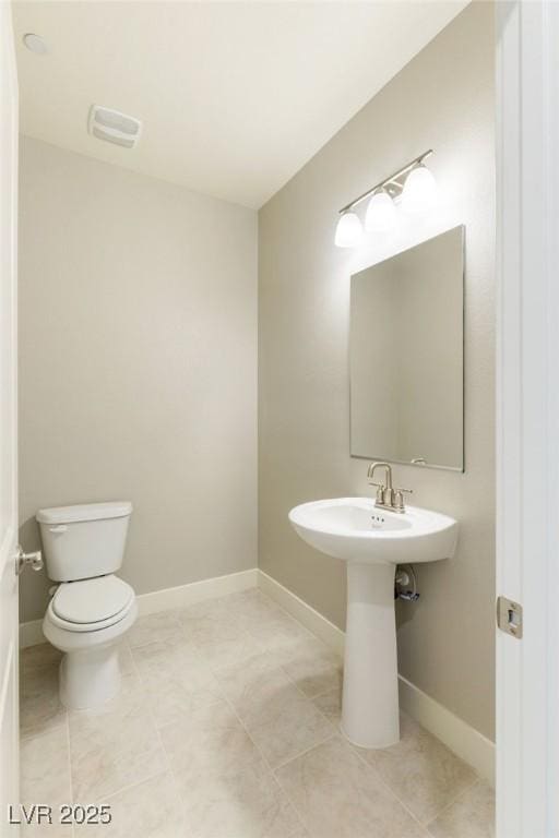 half bathroom featuring toilet, visible vents, baseboards, and tile patterned flooring