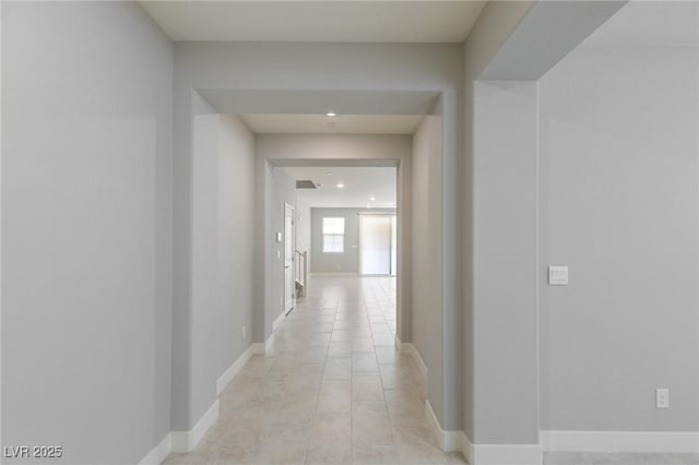hall featuring light tile patterned floors and baseboards