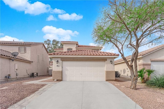 mediterranean / spanish-style home with an attached garage, central AC, concrete driveway, a tiled roof, and stucco siding