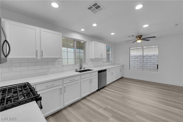 kitchen with visible vents, decorative backsplash, dishwasher, white cabinetry, and a sink