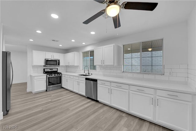 kitchen featuring visible vents, light wood-style flooring, decorative backsplash, appliances with stainless steel finishes, and a sink