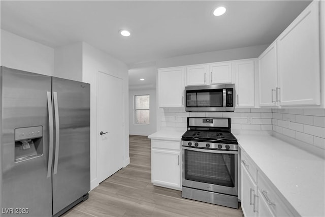 kitchen featuring white cabinets, decorative backsplash, stainless steel appliances, light countertops, and recessed lighting