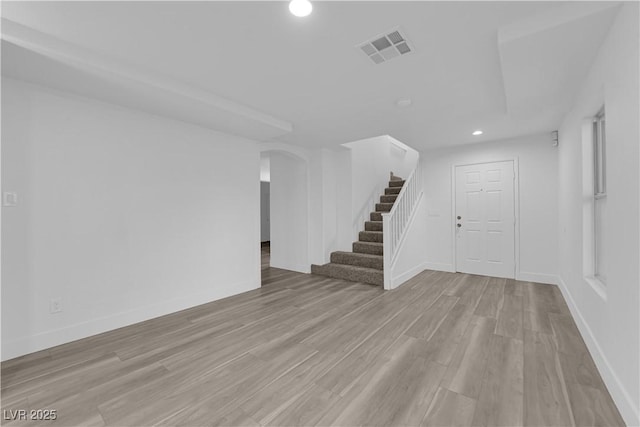 spare room featuring recessed lighting, visible vents, light wood-style flooring, baseboards, and stairs