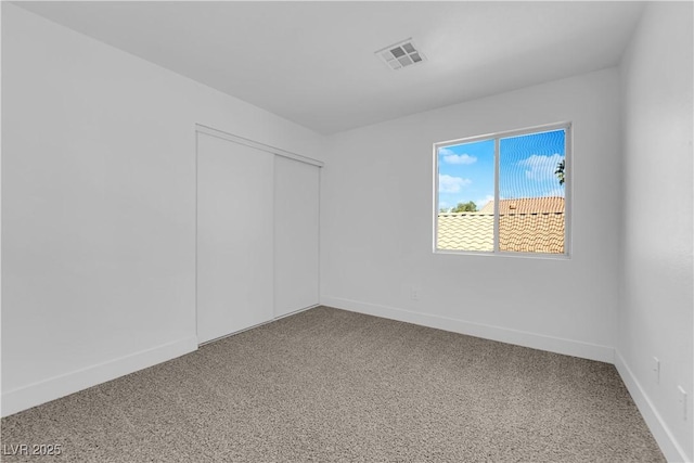 carpeted spare room featuring baseboards and visible vents