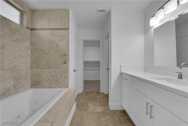 bathroom featuring vanity, visible vents, a spacious closet, a tile shower, and a whirlpool tub