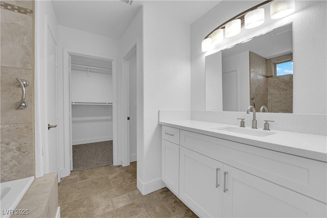 bathroom with baseboards, a tub, a walk in closet, a tile shower, and vanity