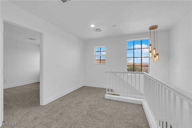 spare room with carpet, visible vents, and baseboards