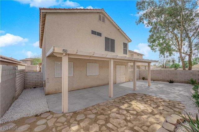 rear view of property featuring a fenced backyard, a patio, and stucco siding