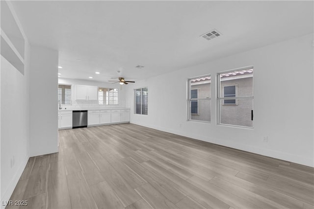 unfurnished living room with visible vents, light wood-style flooring, and baseboards