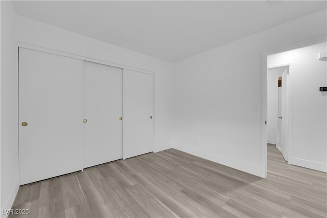 unfurnished bedroom with baseboards, a closet, and light wood-style floors