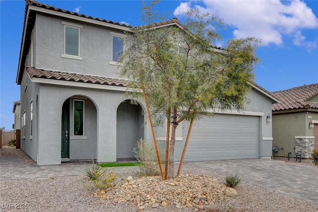 mediterranean / spanish-style home with a tile roof, decorative driveway, and stucco siding