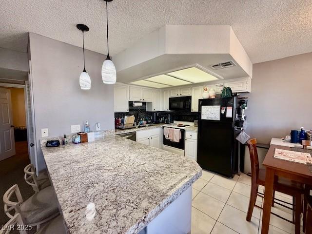 kitchen with pendant lighting, visible vents, white cabinetry, a peninsula, and black appliances