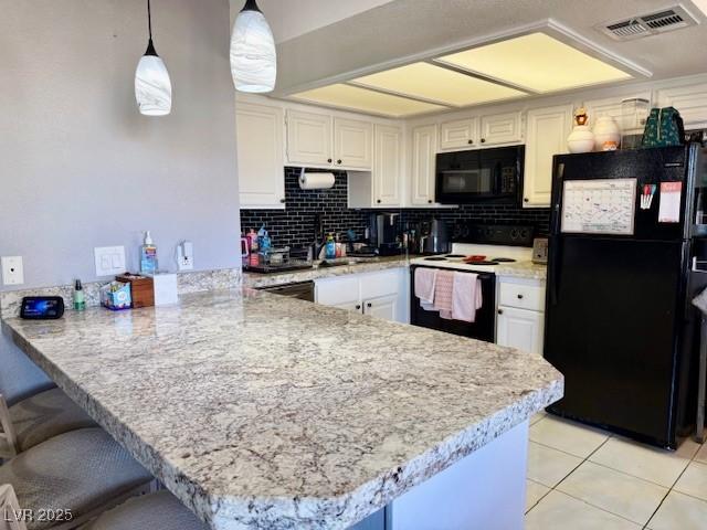 kitchen with tasteful backsplash, visible vents, white cabinets, a peninsula, and black appliances