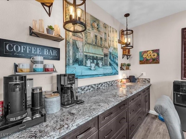 kitchen featuring light stone counters, baseboards, pendant lighting, and wood finished floors